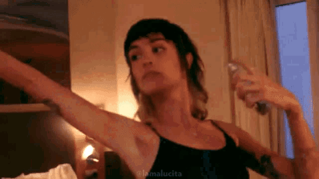 a woman is spraying her armpit with a spray bottle in a room .