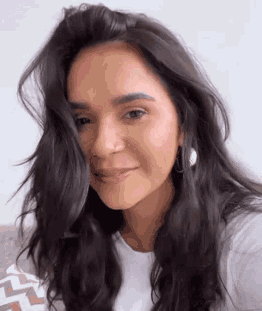 a close up of a woman 's face with long dark hair and earrings .