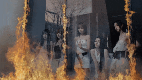 a group of women standing in front of a wall of flames