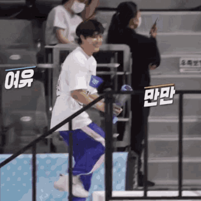 a man in a white shirt and purple pants is standing on a staircase holding a fan .