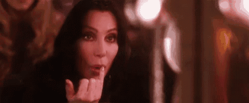 a woman is holding her finger to her lips and making a funny face .