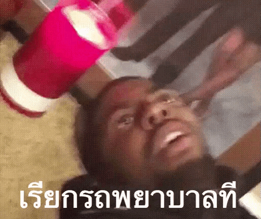 a man is laying on the floor with a red cup on his head in a foreign language .