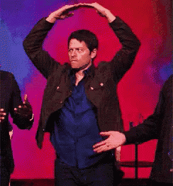 a group of people are dancing on a stage and one of them is holding a microphone