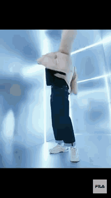 a person is standing in a room with a fila logo on the bottom right corner .
