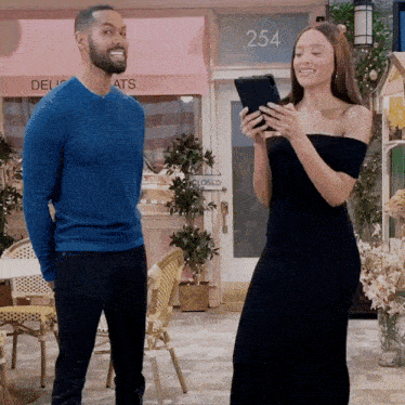 a man and a woman are standing in front of a store with the number 254