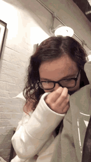 a girl wearing glasses and a white sweater covering her nose