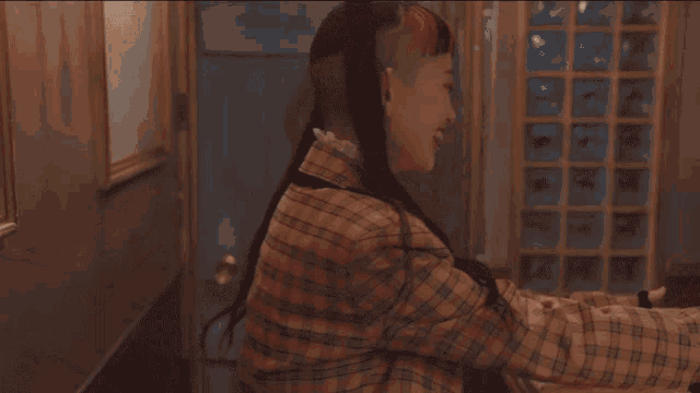 a person wearing a plaid shirt is giving a thumbs up
