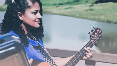 a woman in a blue shirt is holding a guitar with the brand name taylor on it