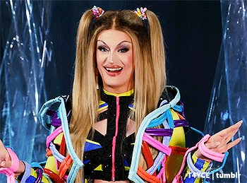 a drag queen is wearing a colorful outfit and holding a bunch of ropes .