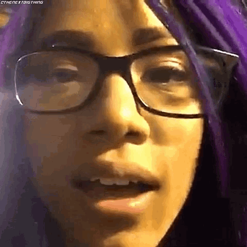 a woman with purple hair and glasses is making a funny face .