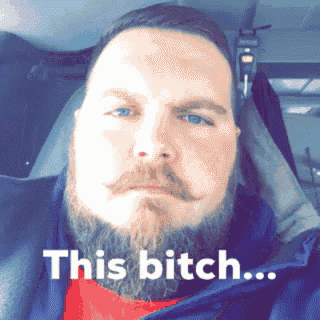 a man with a beard and mustache is sitting in a car with a caption that says this bitch