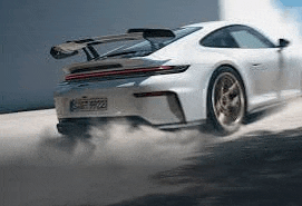 a white porsche 911 gt3 is driving down a road with smoke coming out of its exhaust pipe .