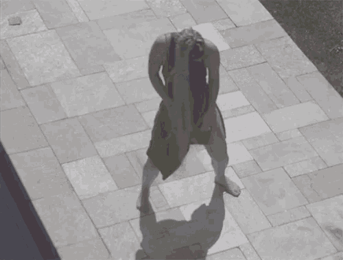 a woman in a black tank top and red pants is standing on a tiled floor