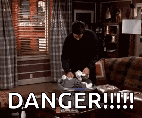 a man is putting clothes in a laundry basket with the word danger written on the bottom