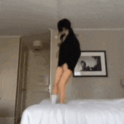 a woman is jumping on a bed in a bedroom