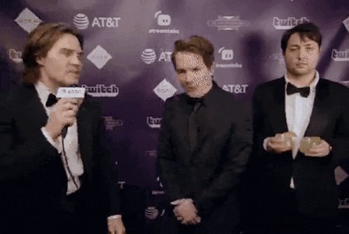 three men in tuxedos are standing in front of a wall with at & t and twitch logos on it