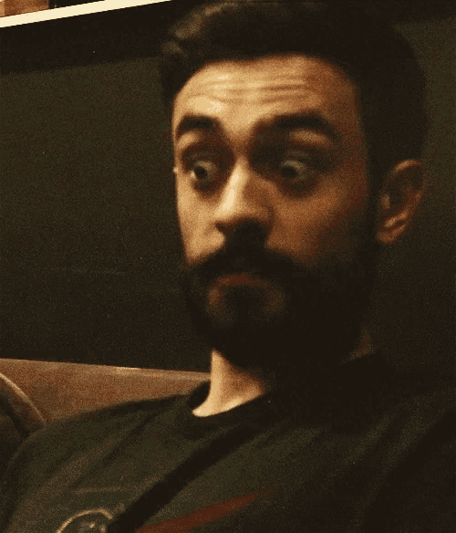 a man with a beard is wearing a black shirt with a green circle on it