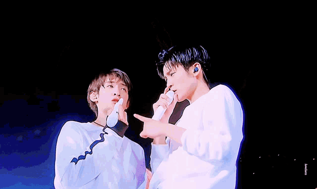 two men are standing next to each other on a stage and one is pointing at the other