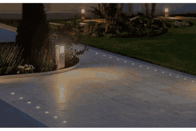 a driveway with a few lights on the sidewalk