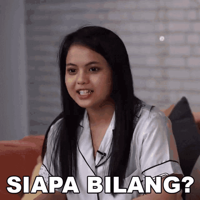 a woman sitting on a couch with siapa bilang written on the bottom