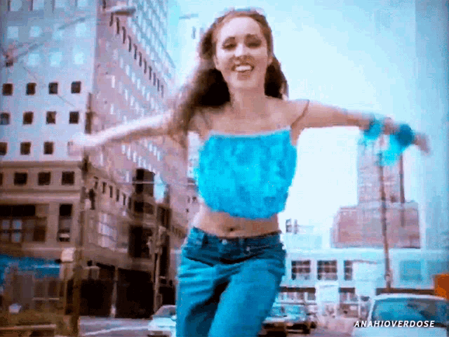 a woman in a blue top and blue jeans is running down a street