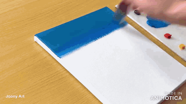 a person is painting a blue and white canvas with a brush