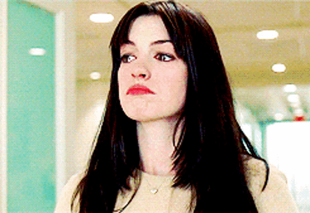 a woman with long dark hair and a heart necklace