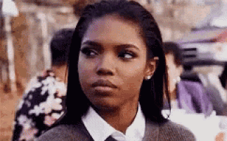 a woman in a sweater and tie is looking at the camera .