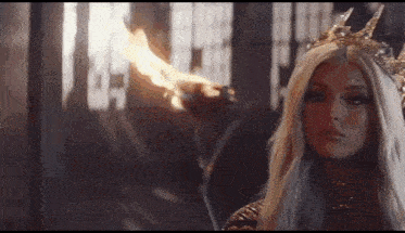 a woman is wearing a crown and holding a torch .