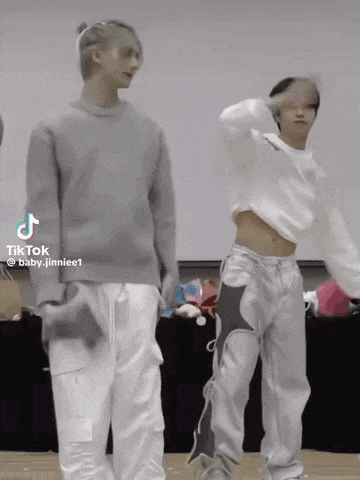 a couple of men are standing next to each other on a stage . one of the men is wearing a crop top .