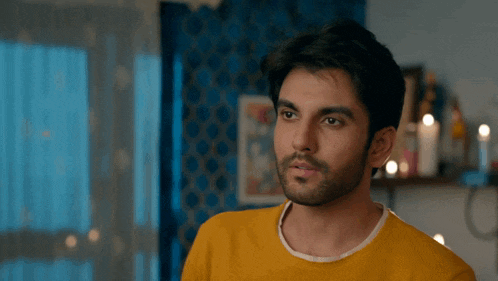 a man with a beard wearing a yellow shirt is looking down