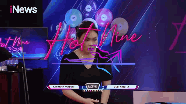 a woman stands in front of a tv screen that says inews