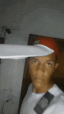 a young man wearing a red hat and a white shirt is holding a knife in his hand .