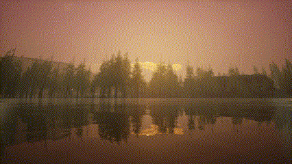 a sunset over a lake with trees in the distance