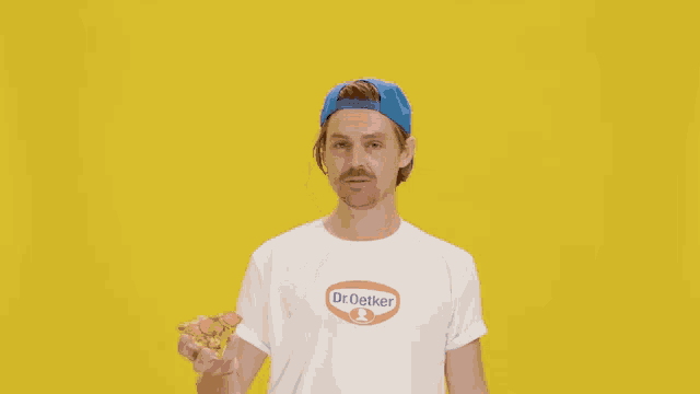a man wearing a dr. oetker shirt is holding a blue object