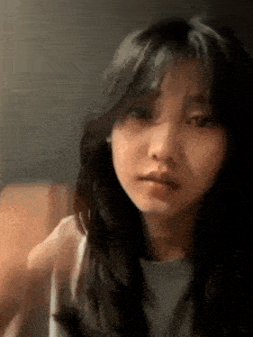 a close up of a woman 's face with long hair and bangs looking at the camera .