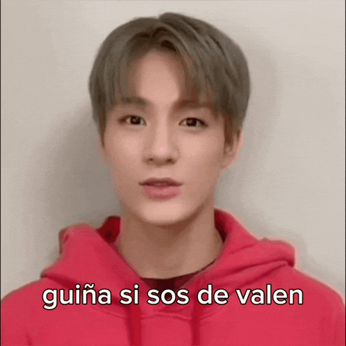 a young man wearing a red hoodie with the words guiña si sos de valen below him