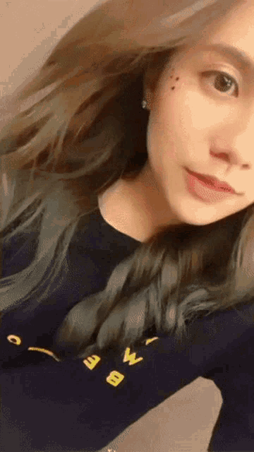 a woman taking a selfie wearing a black shirt with the letter w on the front