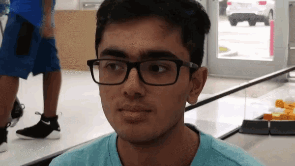 a young man wearing glasses and a blue shirt