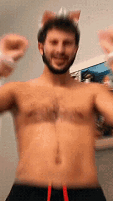 a shirtless man with cat ears on his head is dancing