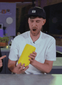 a man in a white shirt and black hat is holding a yellow object in his hands
