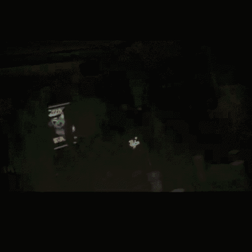 a group of people are dancing in a dark room with a sign that says ' no smoking '