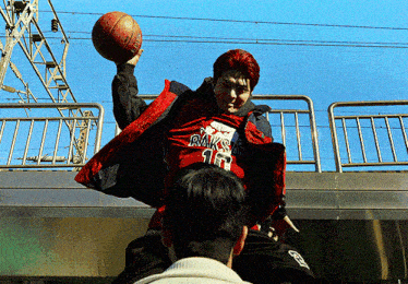 a man wearing a red jacket with raks on it holds a basketball