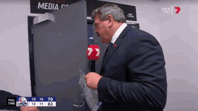 a man in a suit is holding a microphone in front of a door that says media