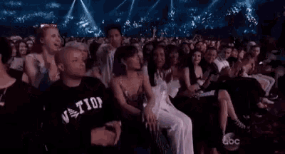 a crowd of people are sitting in a stadium applauding a performance .