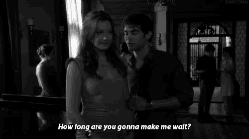 a man and a woman are standing next to each other and the woman is asking the man how long he 's gonna make her wait
