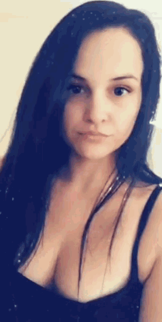 a woman with long dark hair is wearing a black tank top and looking at the camera .