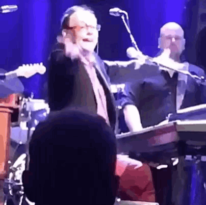 a man is standing on a stage with a microphone and a keyboard .