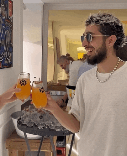 a man wearing sunglasses and a pearl necklace is toasting with a glass of orange juice