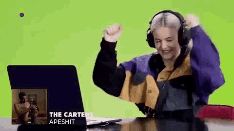 a woman wearing headphones is sitting in front of a laptop with the words the carter 's apeshit on the screen .